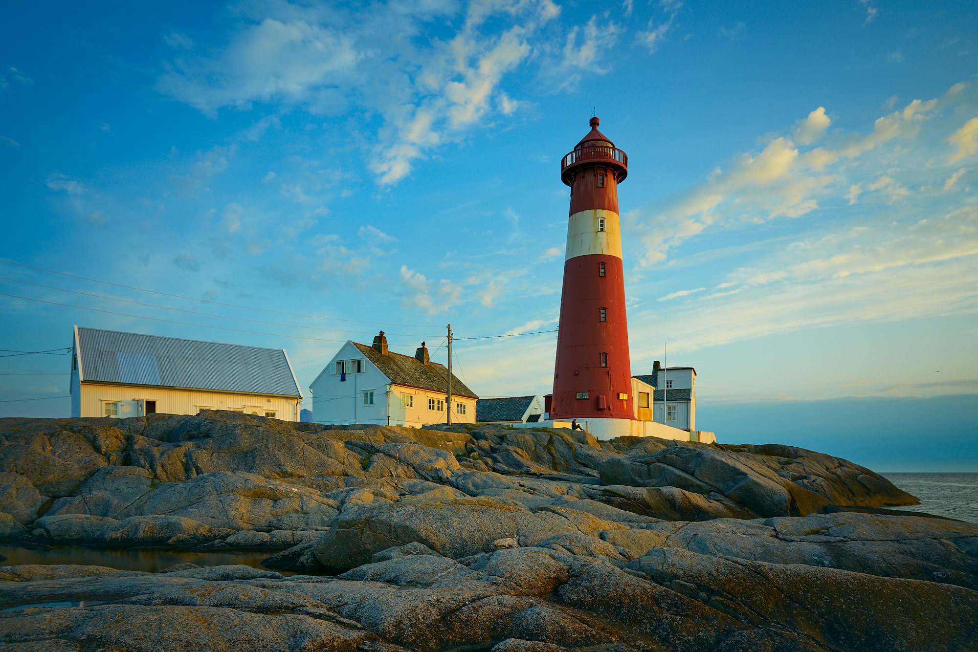 A lighthouse above a quiet beach at sunset